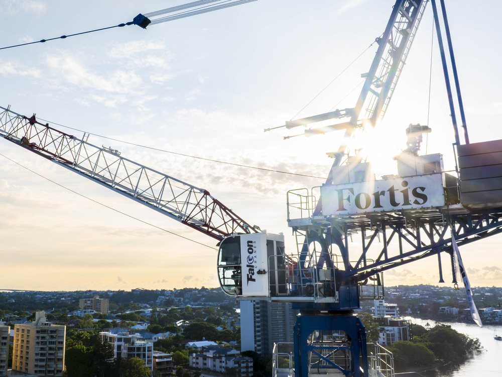 Luffing tower crane lifting a load over a building site