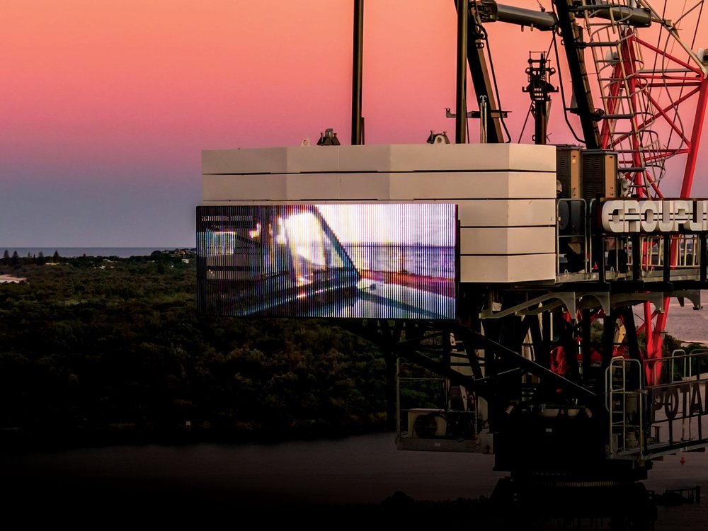 Illuminated SkySigns LED display mounted on a tower crane at sunset
