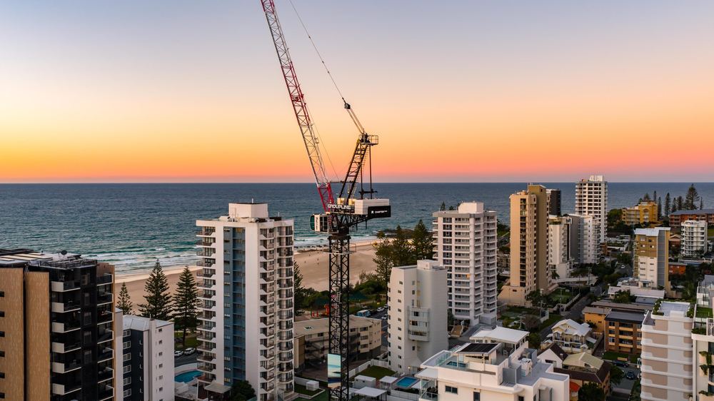 Tower crane above beachfront towers at Rainbow Bay at dusk